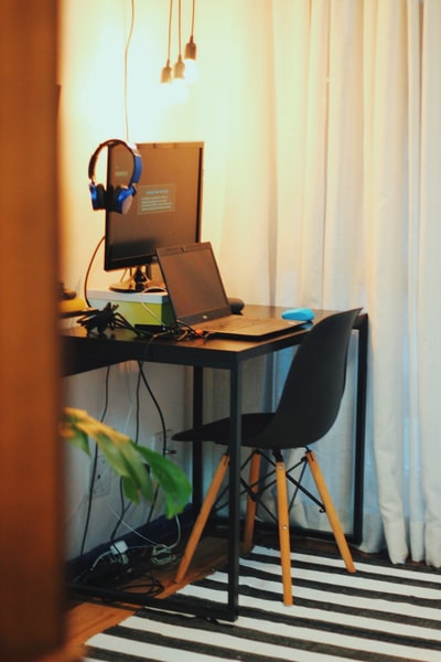带笔记本电脑和显示器的黑色木制办公桌